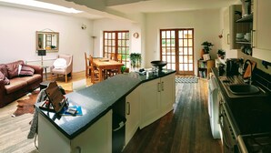 Una cucina moderna con isola centrale, pavimento in legno e zona pranzo con tavolo e sedie.