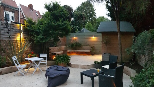 Un'area patio con un braciere, posti a sedere e piante.
