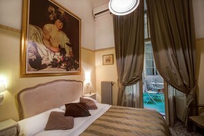 A hotel room with a large bed, a nightstand, a painting, a window with curtains, and a view of the outside. - Tourist House Duomo (Florence)