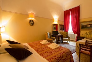 A hotel room with a large bed, two armchairs, a small table, and a television. - Tourist House Duomo (Florence)