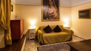 A room with a sofa, two bedside tables with lamps, a framed painting on the wall, and a wooden cabinet. - Tourist House Duomo (Florence)