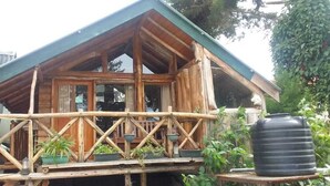 A wooden cabin with a balcony, a large black water tank, and potted plants. - Eco Creations Nuwaraeliya (Nuwara Eliya)