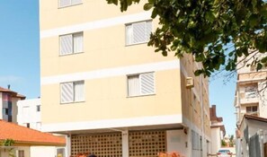 A multi-story building with a yellow facade, multiple windows with shutters, and a visible balcony area.