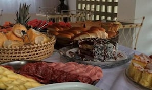 A buffet table with various food items including bread, pastries, and a slice of cake.