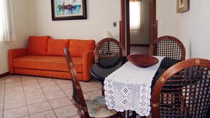 Un saló amb un sofà, una taula amb estovell blanc, cadires de vimet i un quadre encimbellat a la paret.