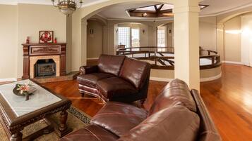 A spacious living room with a fireplace, leather sofas, and a wooden coffee table.