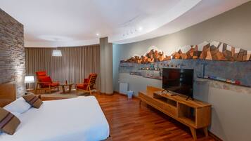 A hotel room with a large bed, a TV, a wooden bench, and a wall-mounted TV shelf.