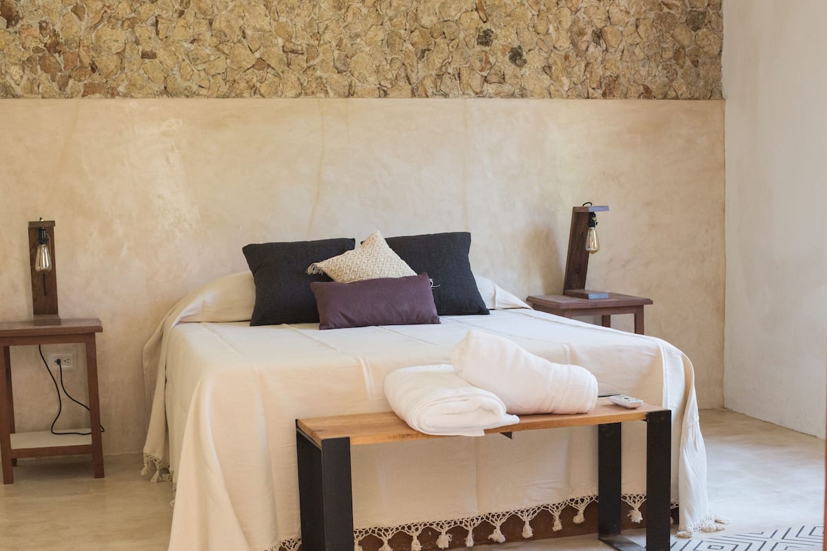 A neatly arranged bedroom with a bed, pillows, a bedside table, and a nightstand.