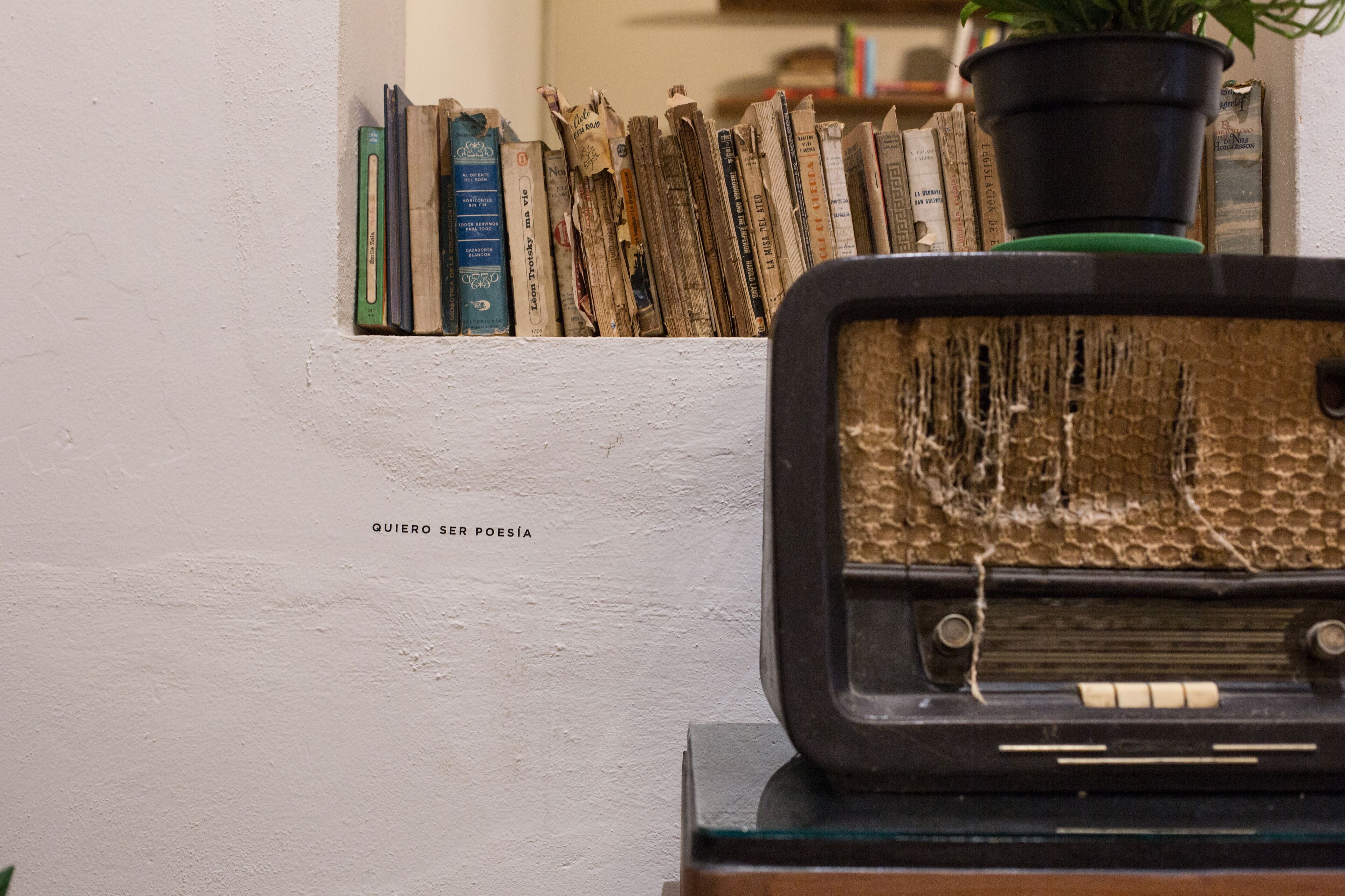 A wall with a shelf of books and a vintage radio.