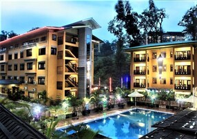A hotel with multiple floors, outdoor pool, and surrounding greenery.