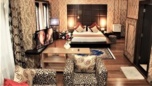 Een hotelkamer met een groot bed, een televisie, een bureau en gestreept meubilair.