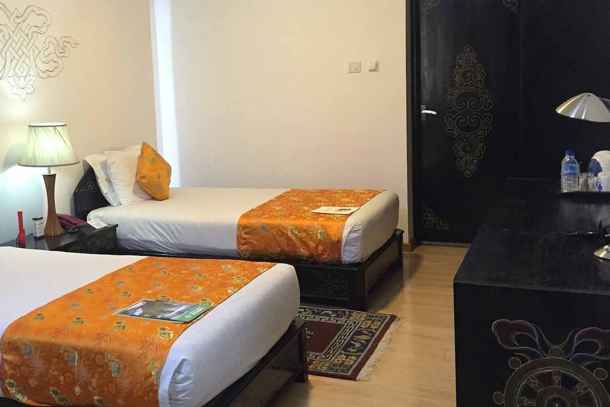 Habitación de hotel con dos camas, un escritorio, una lámpara y un adorno de pared.