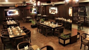 Een restaurant met meerdere eettafels, stoelen, plafondventilatoren en televisies aan de muur.