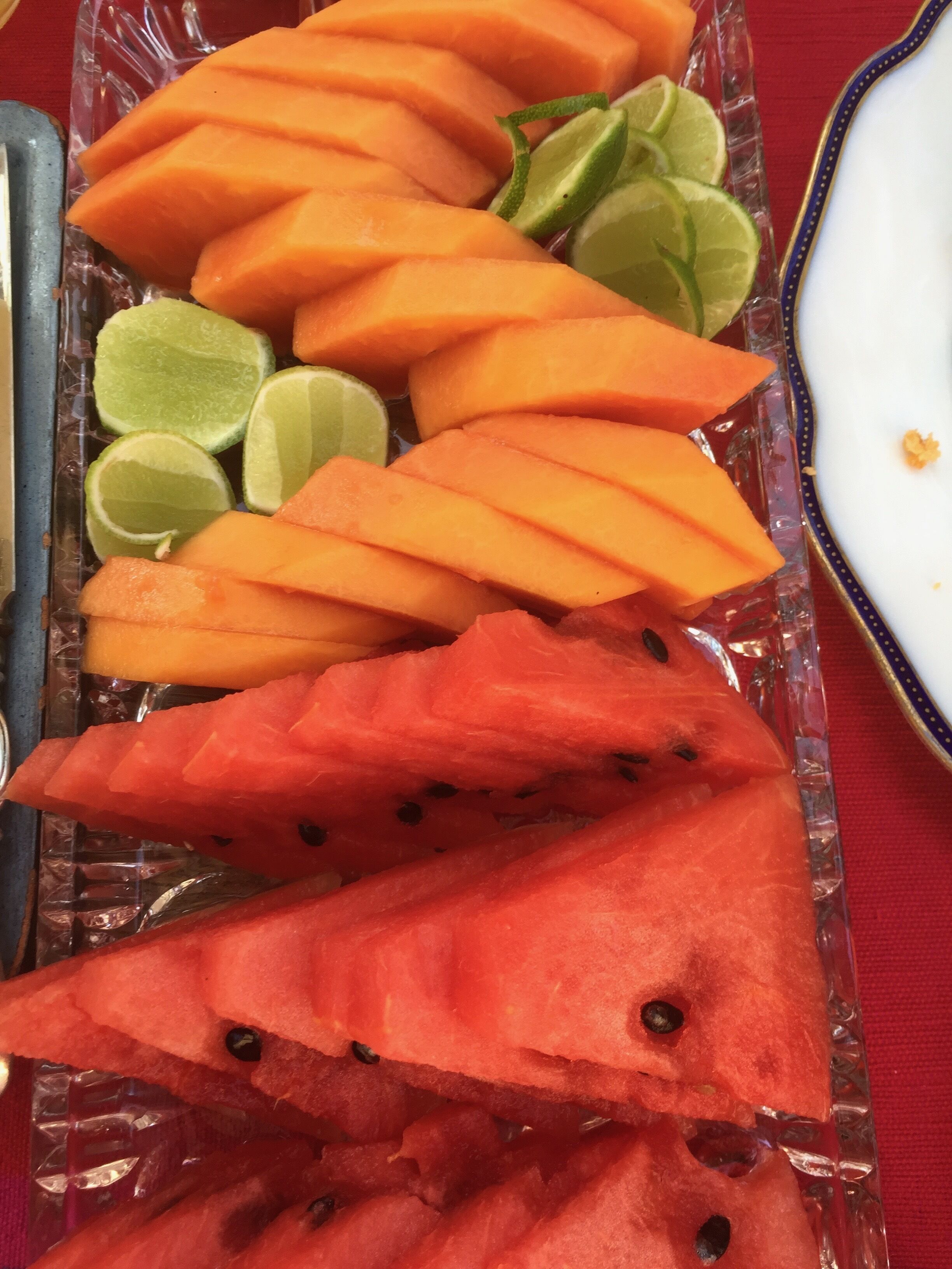 A tray of sliced cantaloupe and watermelon with lime wedges.