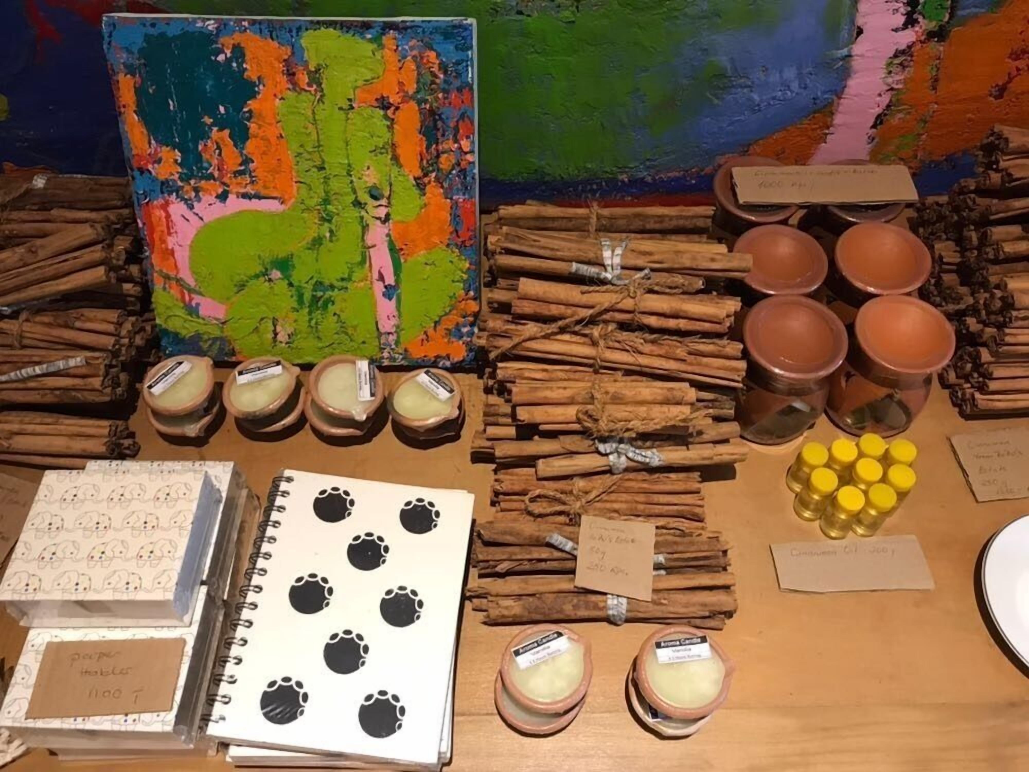 Uma mesa com vários itens, incluindo paus de canela, pequenos potes e um caderno com pegadas.