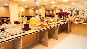Un buffet proposant une variété de plats et de boissons, un lustre et un miroir qui reflète la pièce.