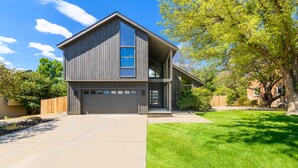 Een modern huis met twee verdiepingen, een garage, een groot raam en een verzorgd gazon.