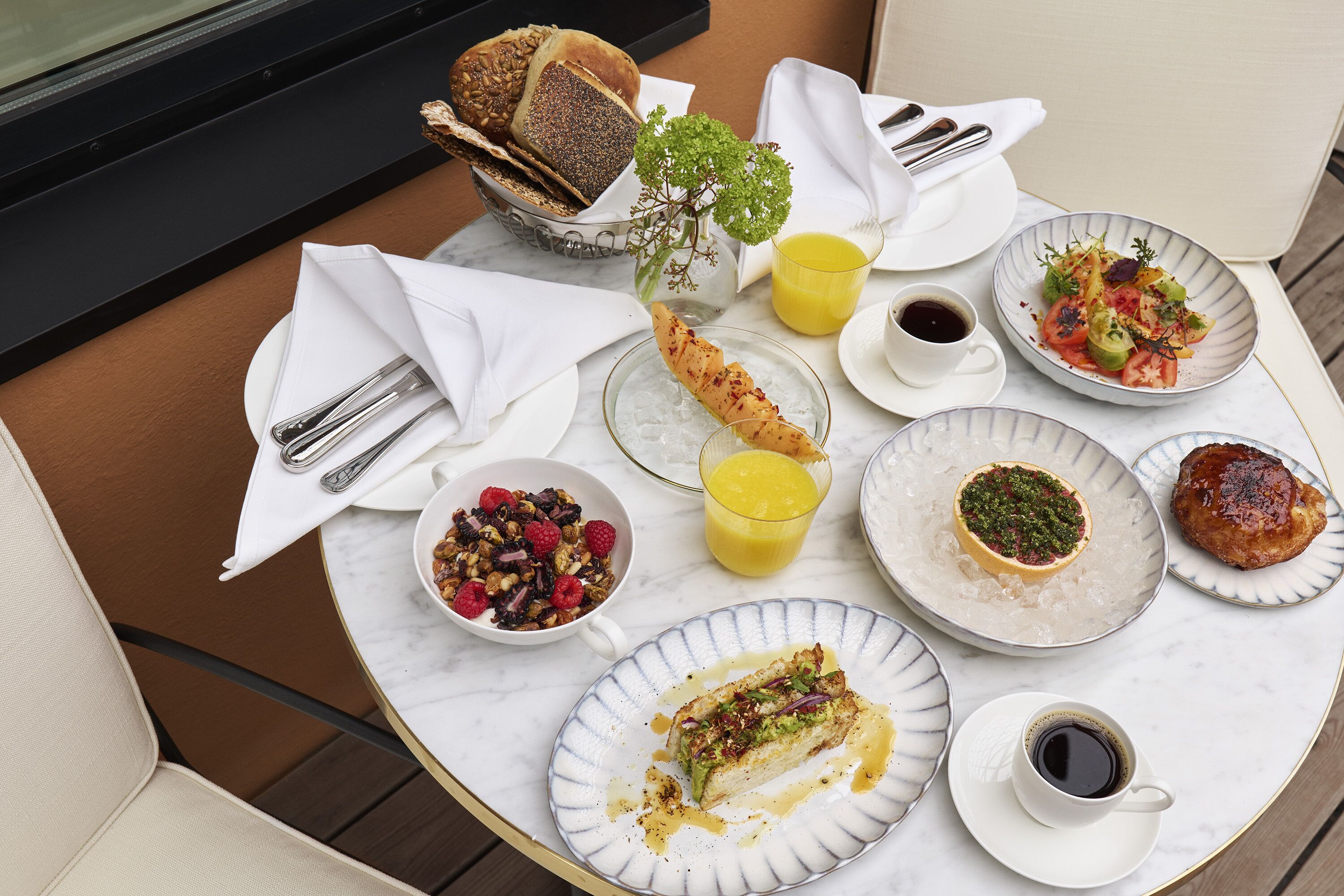A table with breakfast items including bread, fruit, and a dessert.