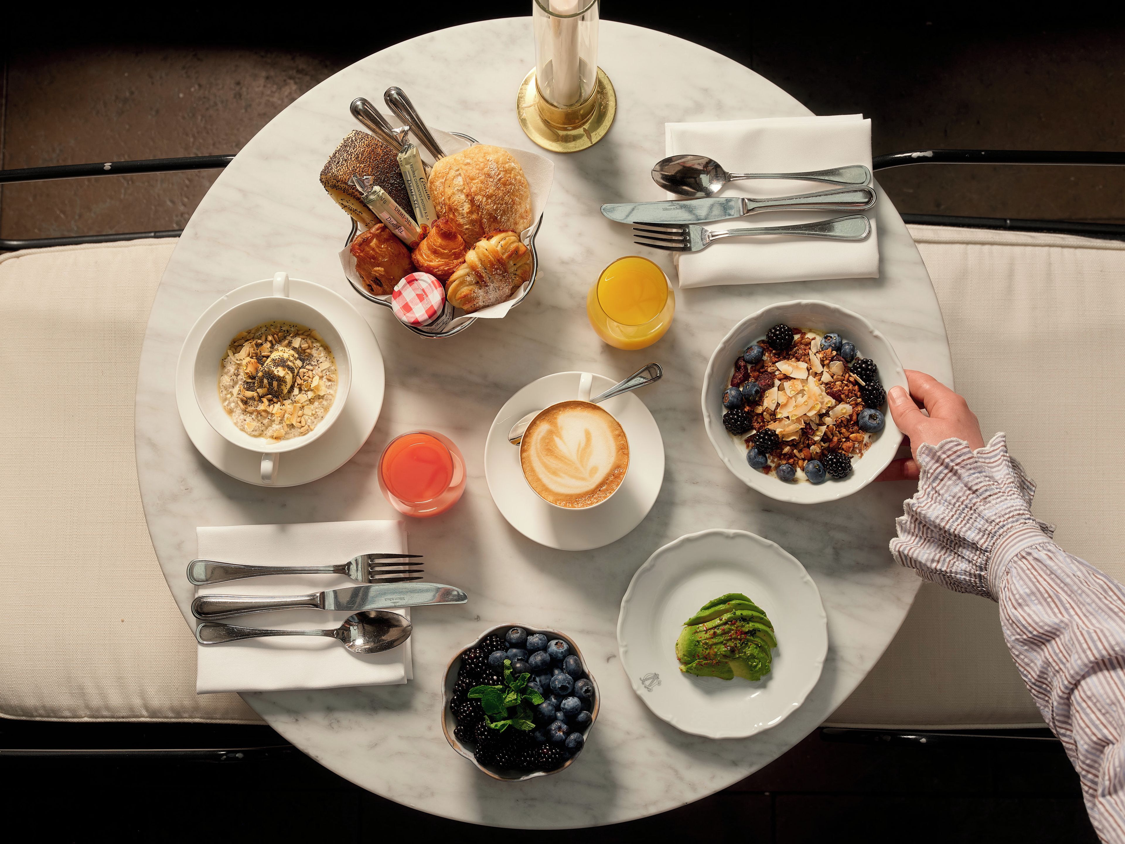 En morgenmadsopstilling med forskellige retter, et glas appelsinjuice og en kop kaffe på et rundt bord.