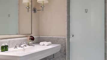 Un bany amb un lavabo blanc, dues làmpades penjades a la paret, un mirall i una porta de dutxa de vidre.