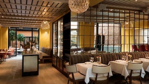 A restaurant interior with a long dining table, cushioned seating, and a decorative ceiling. - Villa Dagmar (Stockholm)