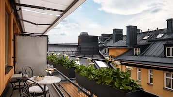 Ein Balkon mit Tisch und Stühlen, einem weißen Baldachin und Blick auf die Nachbargebäude.