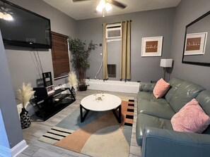 Relax in this stylish living room with a flat-screen TV, comfortable sofa, and a round coffee table.