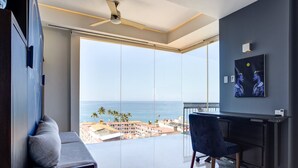 A modern room with a large balcony, a desk, and a TV. - Pier 57 Stunning Ocean View Corner Unit w/ Balcony (Emiliano Zapata)