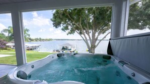 Een hottub met uitzicht op een meer en een steiger.