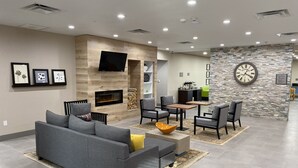 Un salon moderne avec une cheminée, un canapé gris et un coin repas comprenant des chaises et une table.
