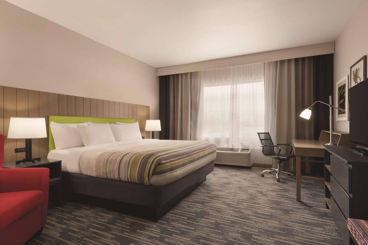 A hotel room with a large bed, two bedside tables with lamps, a desk with a chair, and a television.