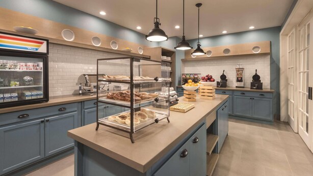 Une cuisine moderne dotée d’un îlot central, d’un réfrigérateur et d’un espace dédié à la préparation du café.
