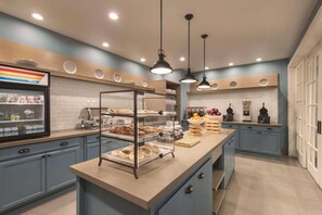 Una cuina moderna amb una illa central, un frigorífic i una zona de cafè.