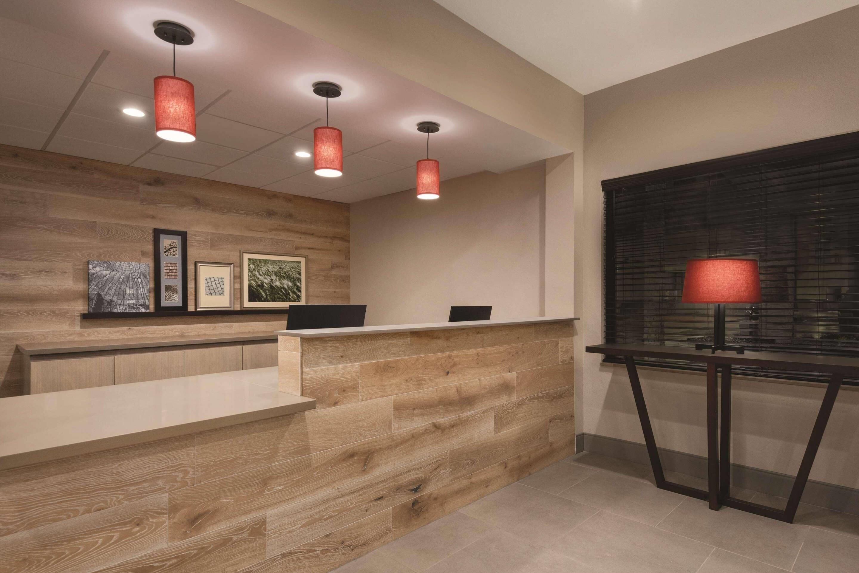 A reception area with a wooden reception desk, three pendant lights, and framed artwork on the wall.