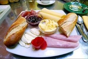 A plate with various food items including bread, cheese, ham, and a red rose. - Hotel DK (Ouidah)