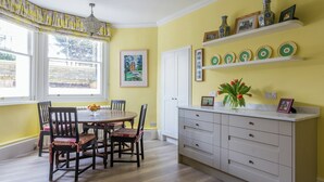 A dining area with a round table, chairs, and a white cabinet with drawers.