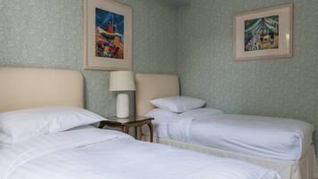 A hotel room with two beds, a nightstand, a lamp, and two framed pictures on the wall.