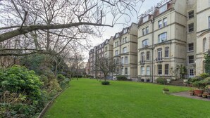 A courtyard with a lawn and a row of terraced houses.