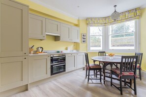 A kitchen with beige cabinets, a dining table with chairs, and a window with a view of the outdoors. - Elm Park Gardens XI by Onefinestay (London)