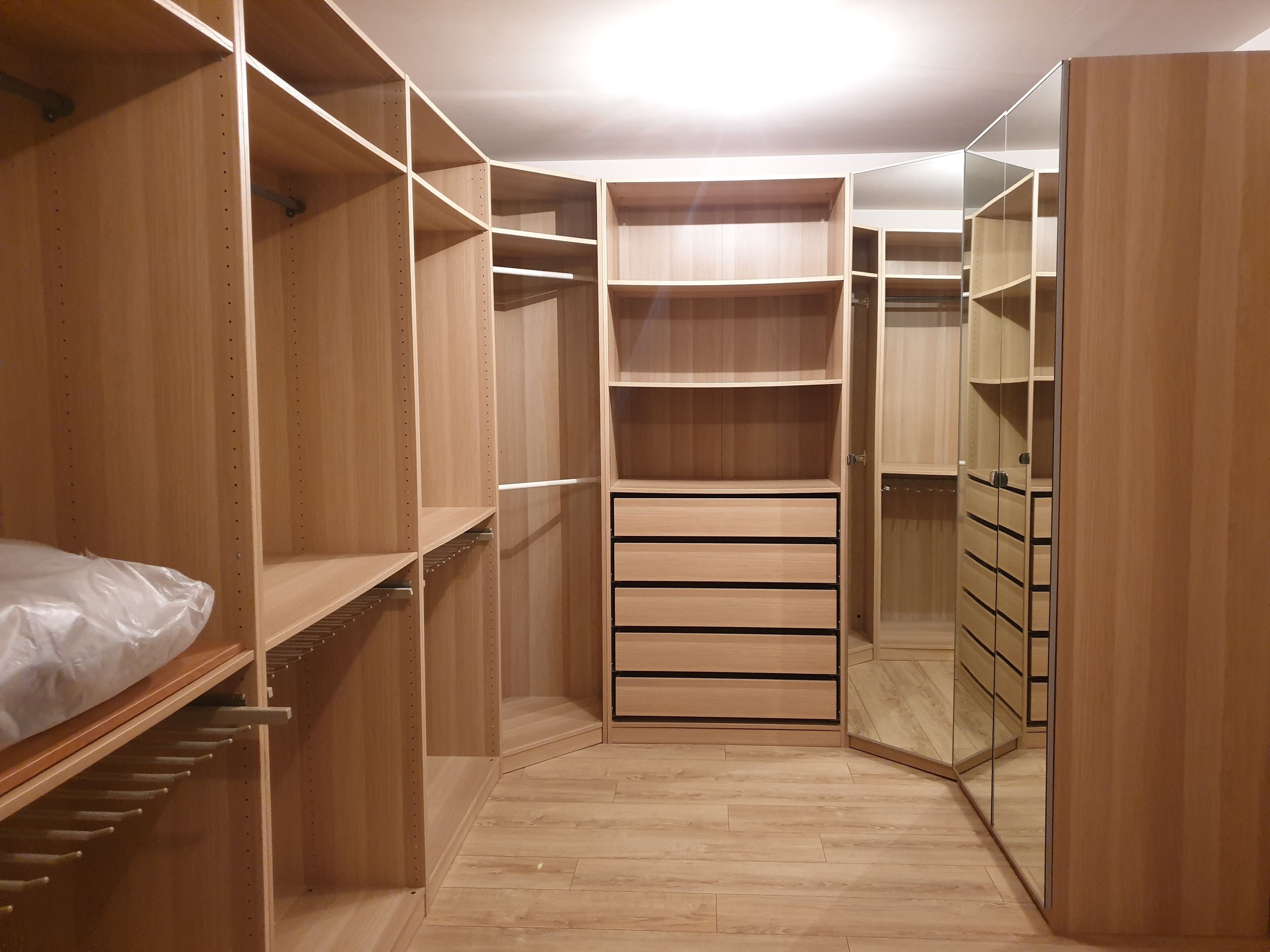 Un dressing avec des étagères en bois, des tiroirs et une section avec un miroir.