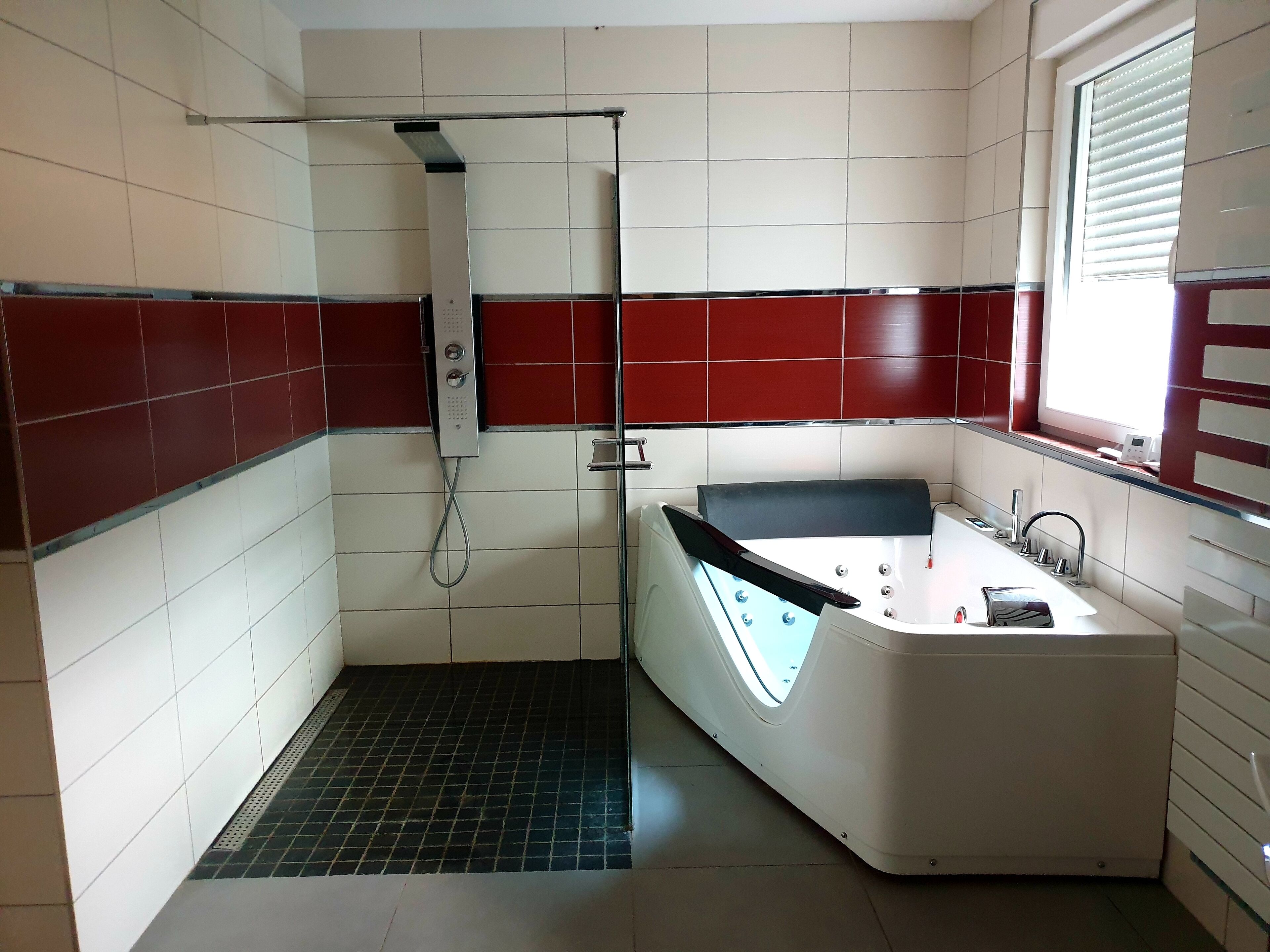 A bathroom with a bathtub, a shower, and a window.