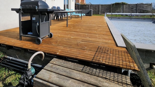 Une terrasse extérieure équipée d’un barbecue, d’une piscine et d’un sol en bois.