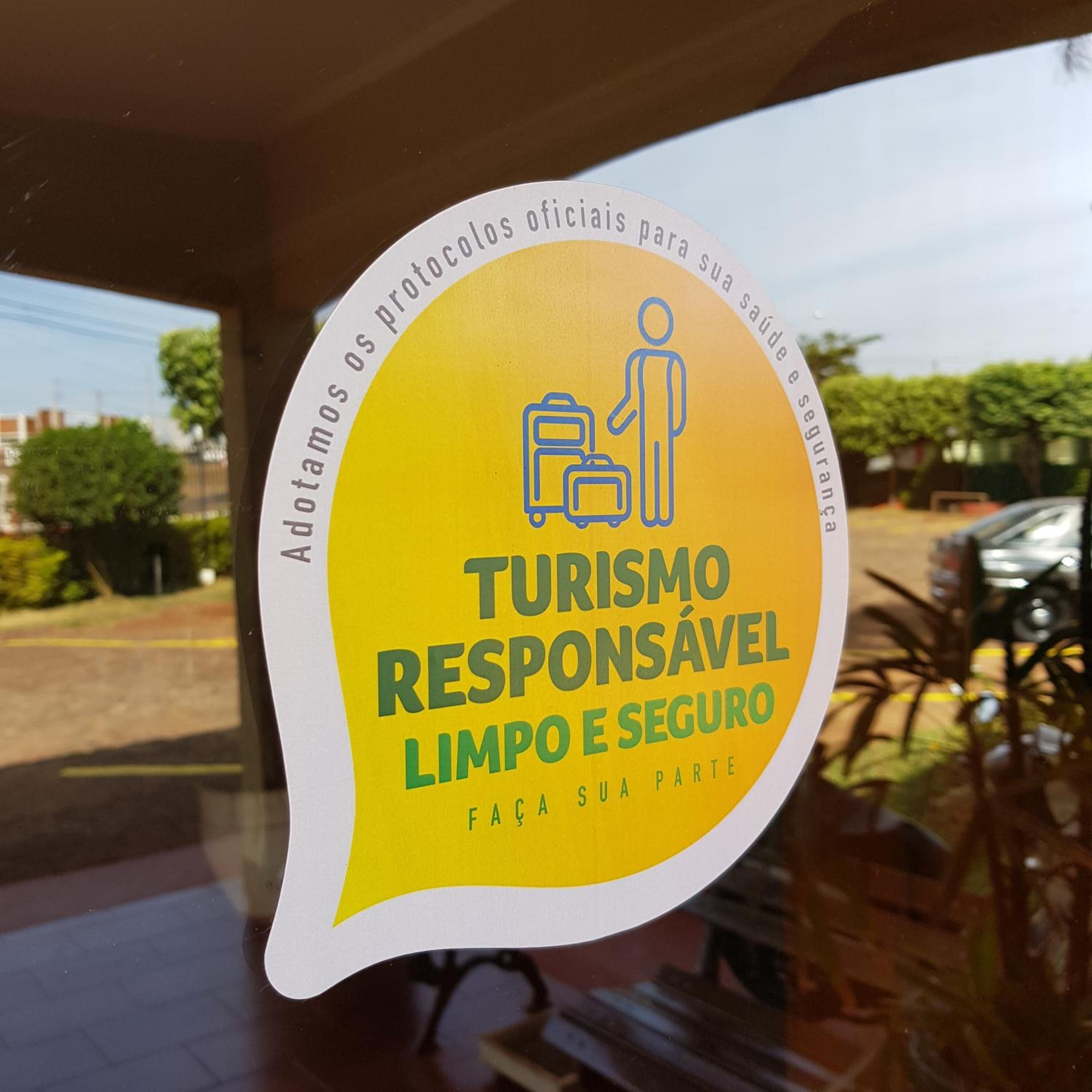 A sticker on a window with the text "Turismo Responsável Limpo e Seguro" and an icon of a person with luggage.
