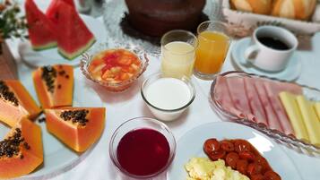 A breakfast table with various food items including eggs, sausages, ham, and pastries.
