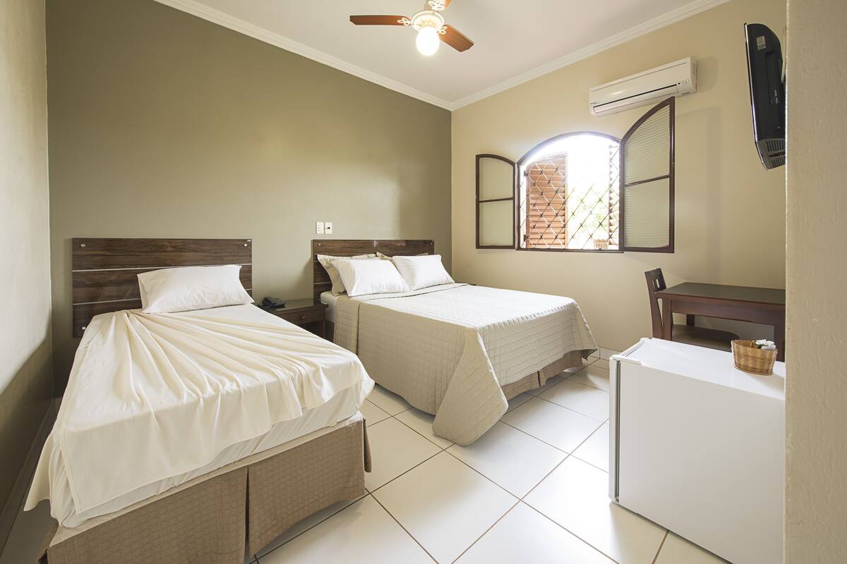 A bedroom with two beds, a desk, and a ceiling fan.