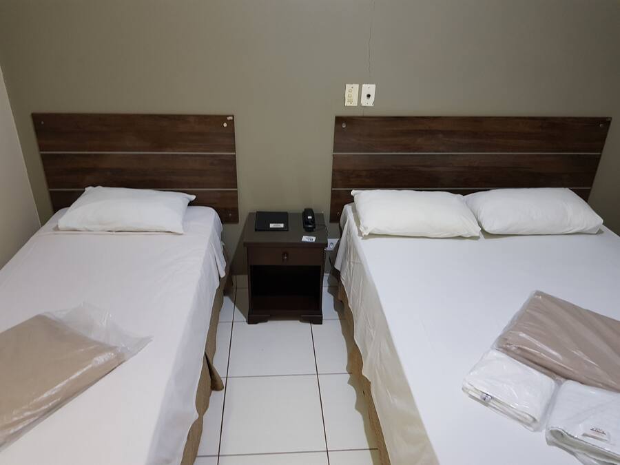 Una habitación de hotel con dos camas, una mesita de noche y un enchufe en la pared.