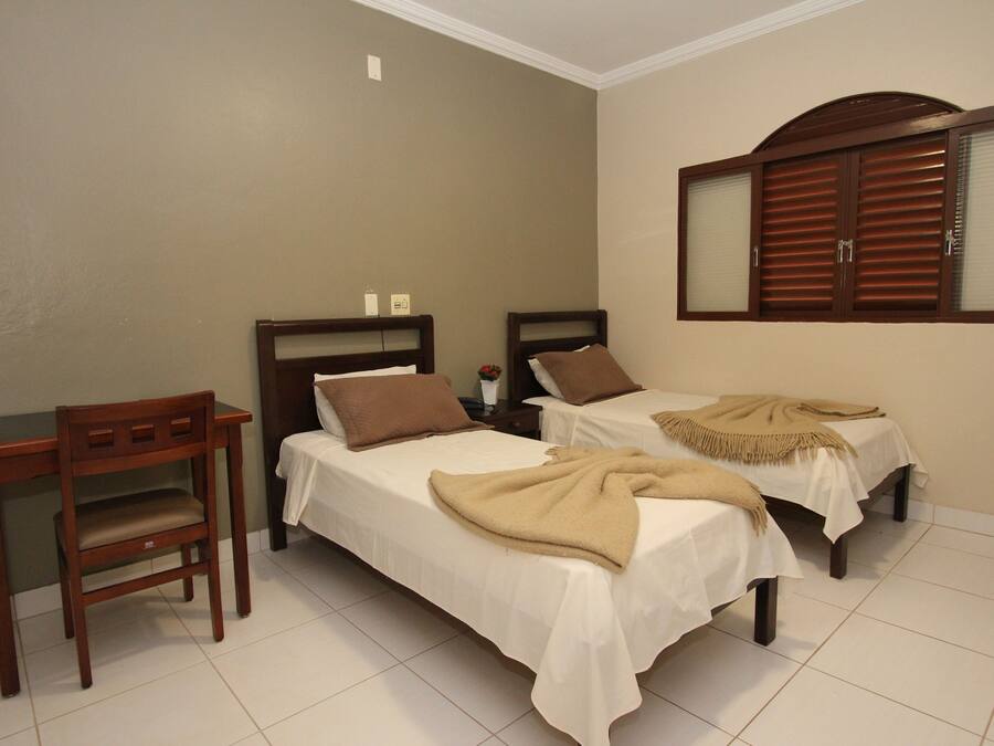 Un dormitorio con dos camas individuales, un escritorio de madera y un espejo con contraventanas de madera.