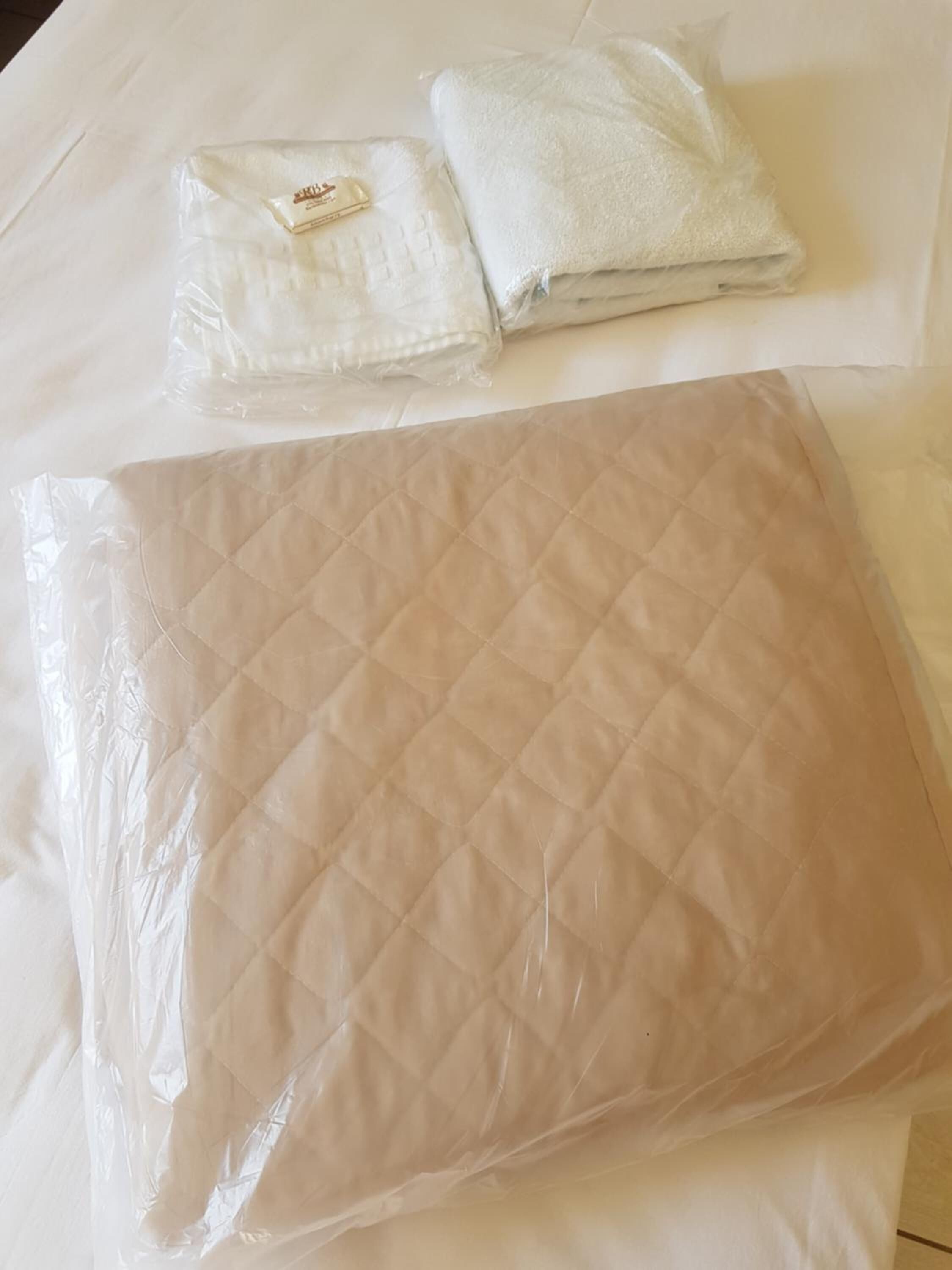 Cama com um edredom acolchoado e toalha dobrada.
