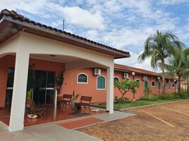 Un edificio con acceso cubierto, mesas al aire libre y un estacionamiento.