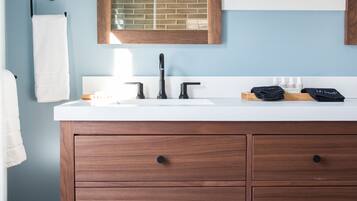 A bathroom with a wooden vanity, a white sink, a mirror, and a window.